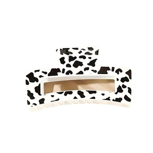 Minimalist rectangular hair claw clip with black and white cow print on white background
