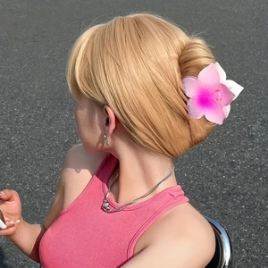 Pince à cheveux fleur rose à cinq pétales portée sur un chignon élégant par un mannequin