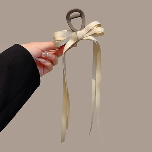 Dettaglio di un elegante fermaglio per capelli con fiocco crema e lunghi nastri