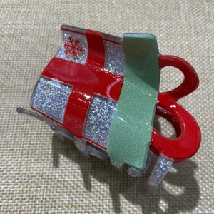 Close-up of a Christmas hair claw with red and green patterns and silver glitter detail