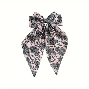 Detail view of pink paisley pattern satin bow hair clip with long elegant ribbons