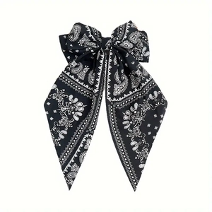 Detail of a vintage black paisley bow hair clip with long flowing chiffon streamers
