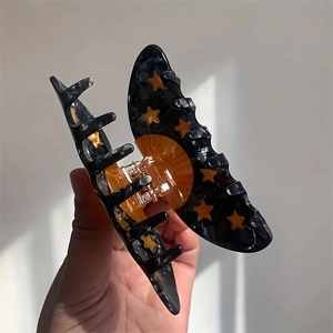 Detail of butterfly-shaped acetate hair claw with yellow stars and marble pattern