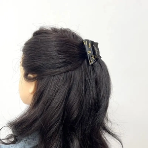 Detail of a black cat hair claw clip with gold facial lines worn on long wavy hair