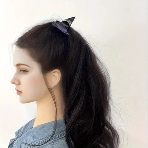 Detail showing a black witch hat hair claw clip with purple ribbon worn on long dark hair