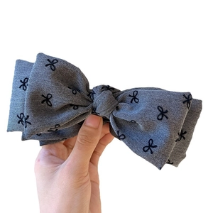 Elegant grey fabric hair claw clip with black bow pattern for high ponytail hairstyle