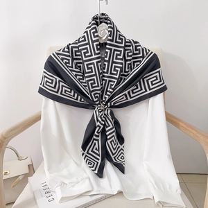 Detail of a black and white Greek key pattern silk scarf styled on a white shirt