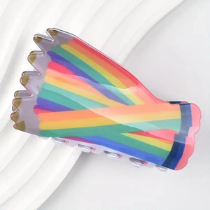 Close-up of a colorful rainbow striped hair claw clip on a white textured tray