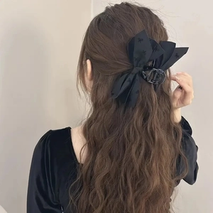 Detailed back view of a black fabric bow hair claw clip styled on long wavy hair
