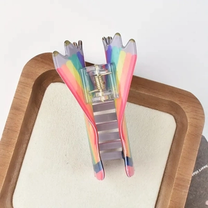 Rainbow striped translucent hair claw clip with golden metal spring on wooden tray