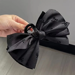 Detailed view of black bow hair claw clip with textured jacquard fabric pattern