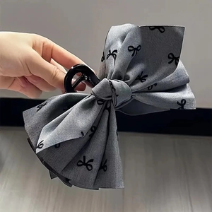 Detail of grey ribbon hair claw clip featuring black bow pattern for high ponytail styles