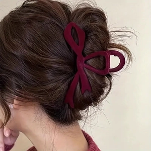 Macro detail of burgundy velvet bow hair claw clip styled on elegant brunette hair