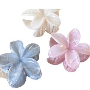Three elegant plumeria flower hair claws in blue, pink, and cream with marble texture
