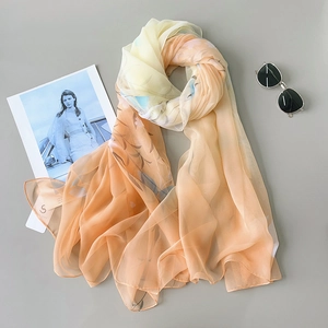 Detail of soft yellow and orange gradient floral scarf with sunglasses and magazine
