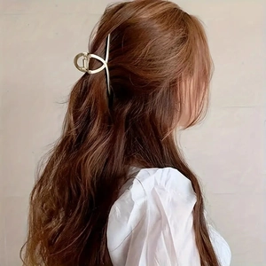 Elegant gold hollow metal claw clip for women holding a ponytail on brown wavy hair
