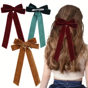 Detail view of velvet bow hair clips in wine red, dark green and caramel with metal clips