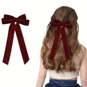 Deep red velvet bow hair clip with long ribbons shown on model for elegant style
