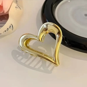 Detalle de una pinza para el cabello de metal dorado con diseño de corazón