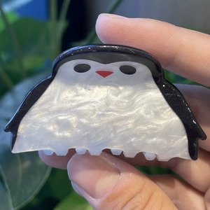 Vista detallada de la pinza de pelo de pingüino con textura de acetato nacarado y diseño