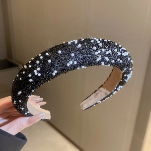 Détail d'un serre-tête éponge avec strass noirs et perles blanches avec doublure antidérapante