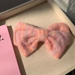 Barrette à cheveux avec nœud en peluche rose et perles sur un plateau décoré