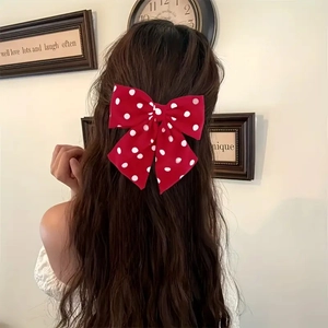 Close-up of red and white polka dot fabric bow hair clip worn on long wavy hair