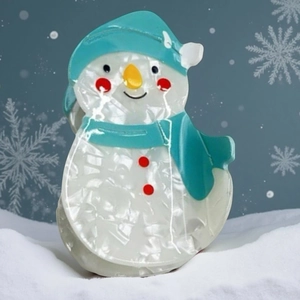 Pince à cheveux bonhomme de neige nacrée pour femme dans un décor de neige hivernal