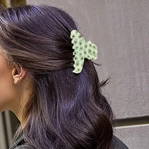 Light green hair claw clip with avocado print on model wavy hair shown from side view