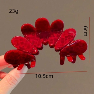Detail view of red flower hair claw with dimensions 10.5cm by 6cm and textured finish
