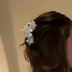 Gros plan sur la pince à cheveux fleurs de frangipanier blanches au fini nacré