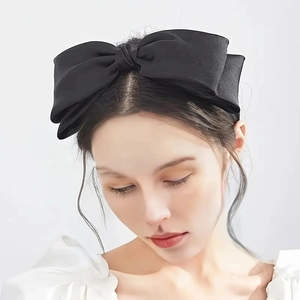 Elegante cerchietto con doppio fiocco in raso nero per donna su sfondo grigio chiaro