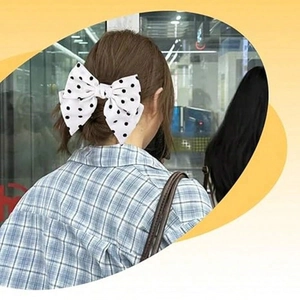 Rear view of model wearing a large white hair clip with black polka dot bow