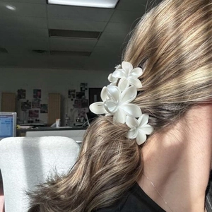 Élégante pince à cheveux fleur de frangipanier blanche portée sur cheveux bruns