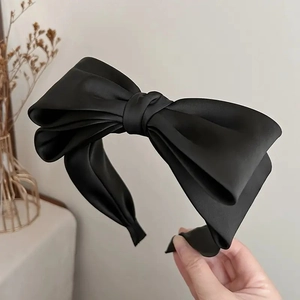 Dettaglio dell'elegante cerchietto in raso nero con un grande fiocco raffinato