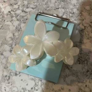 Détail d'une pince à cheveux fleur de frangipanier blanc nacré avec ressort métallique robuste