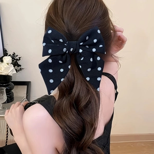 Sweet black and white polka dot bow hair clip on model with wavy brunette hair