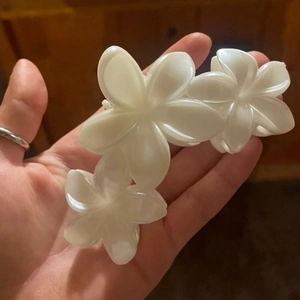 Trois élégantes pinces à cheveux fleur de frangipanier blanc nacré tenues en main