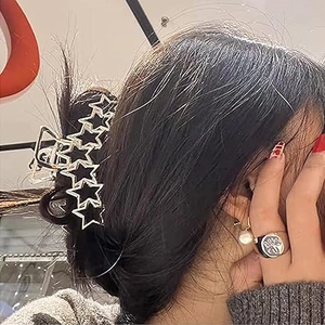 Minimalist black star claw clip with gold edges worn on a ponytail hair bun for women