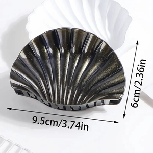 Shell shaped black hair claw clip with gold glitter in white dish, size 9.5cm