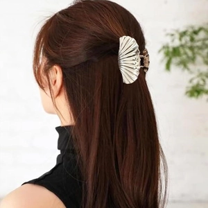 Macro shot of a silver shell-shaped hair claw clip styling long brown hair from behind