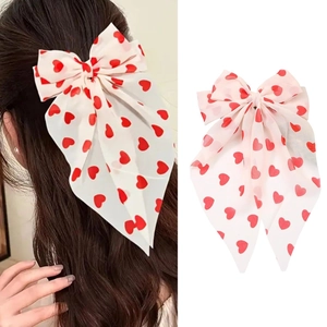 Détail d'un nœud papillon blanc à cœurs rouges et longs rubans pour cheveux