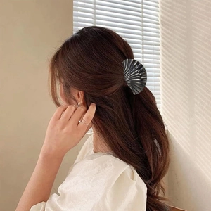 Detailed view of the dark grey shell-shaped hair claw clip on a long wavy hairstyle