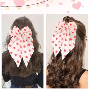 Macro de grande pince à cheveux avec nœud rose à motif cœurs et longs rubans fluides