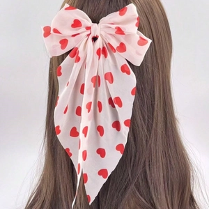 Détail d'un nœud en mousseline rose avec motifs cœurs rouges sur cheveux