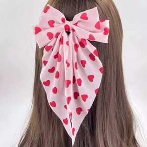 Détail du nœud à cheveux en mousseline rose avec motifs cœurs et longs rubans