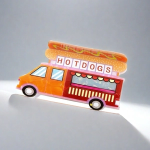 Détail d'une pince à cheveux chariot hot-dog en PVC avec roues orange et texte