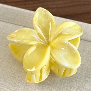 Gros plan d'une pince à cheveux fleur jaune pâle 8cm avec texture marbrée élégante