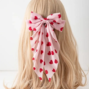 Barrette à cheveux rose avec nœud à motifs cœurs rouges sur cheveux blonds