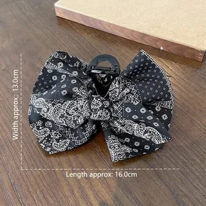 Large black paisley bow hair claw clip for women featuring elegant fabric-covered design